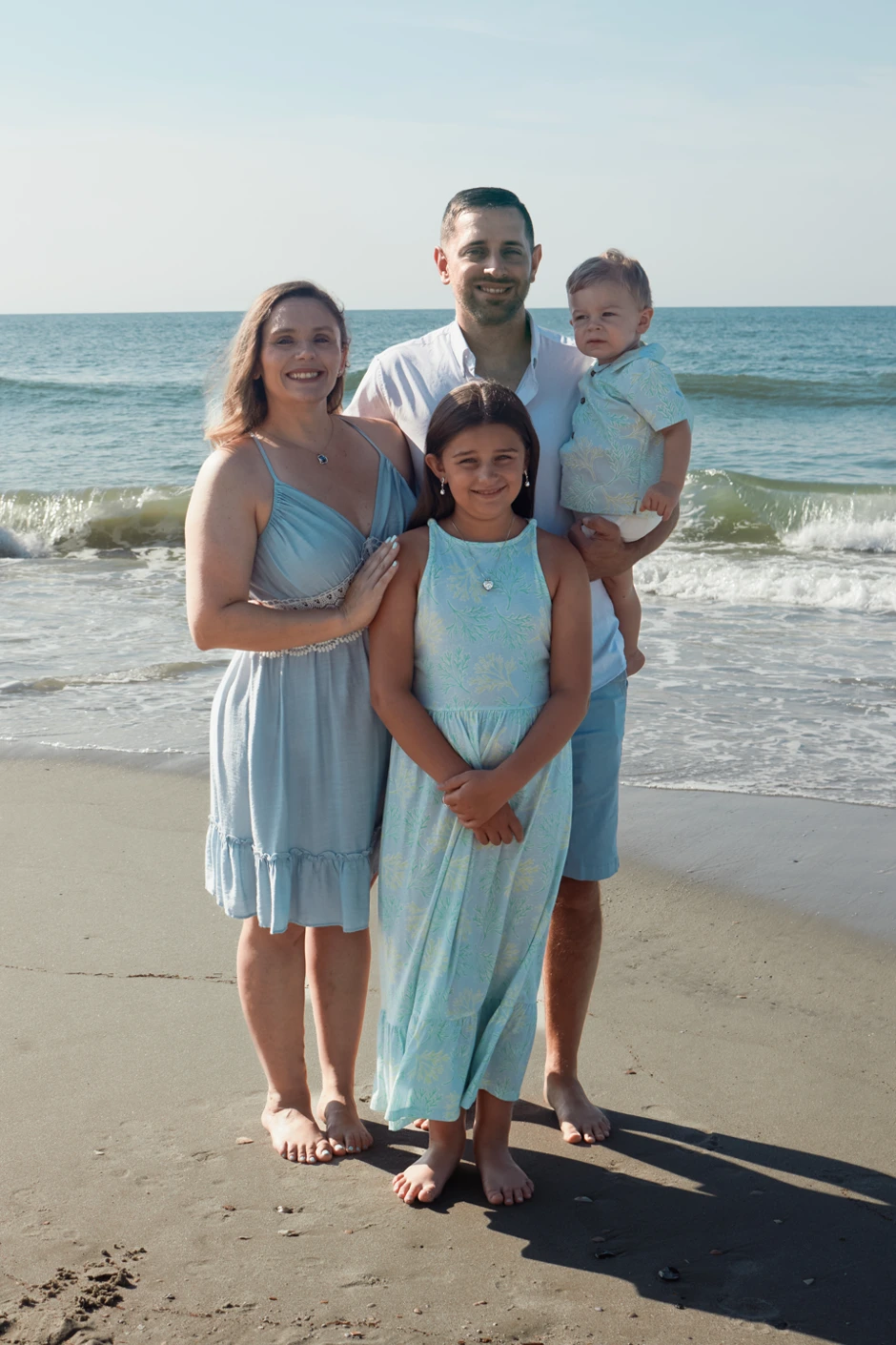 Hailey with her family standing together beside the ocean